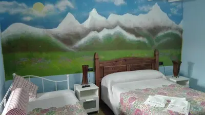 a bedroom with two beds and a mural on the wall at Hotel Rural Casa Indie in Rabanal del Camino