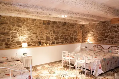 a bedroom with two beds and a stone wall at Hotel Rural Casa Indie in Rabanal del Camino