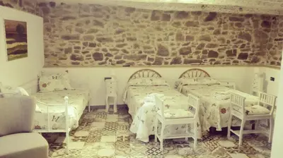 a bedroom with two beds and a stone wall at Hotel Rural Casa Indie in Rabanal del Camino