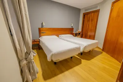 two beds in a room with wooden floors at Hotel Los Templarios in Ponferrada