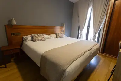 a bedroom with a large white bed with a window at Hotel Los Templarios in Ponferrada