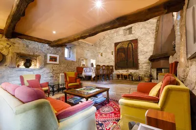 a living room with colorful furniture and a stone wall at Rectoral de Fofe in Fofe
