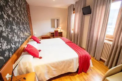a hotel room with a bed with red pillows at Hotel Montero in Mondoñedo