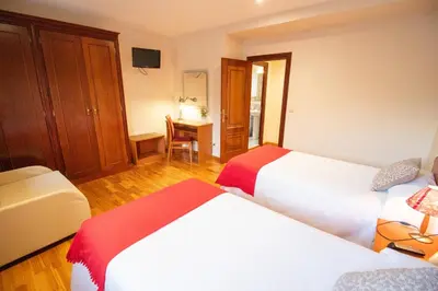 a hotel room with two beds and a desk at Hotel Montero in Mondoñedo