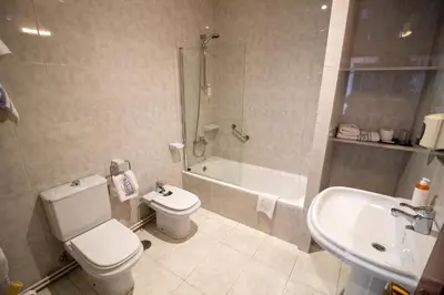 a bathroom with a toilet and a shower and a sink at Hotel Montero in Mondoñedo