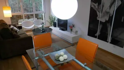 a living room with a glass table and orange chairs at Apartamentos Antares 1 in Milladoiro