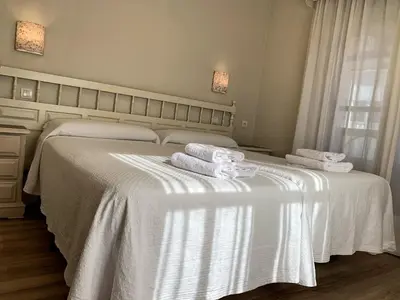 a bedroom with two beds with white sheets and towels at Hostal Restaurante Méndez in Villafranca del Bierzo