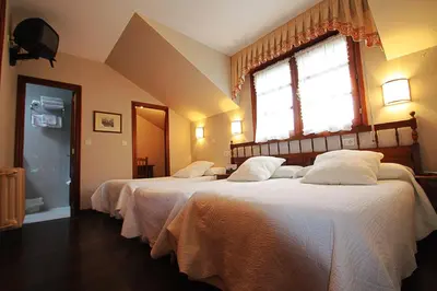 a bedroom with two beds with white sheets and a window at Hostal Restaurante Méndez in Villafranca del Bierzo