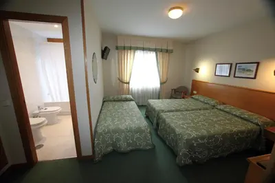 a hotel room with two beds and a bathroom at Hotel Ramos in Silleda