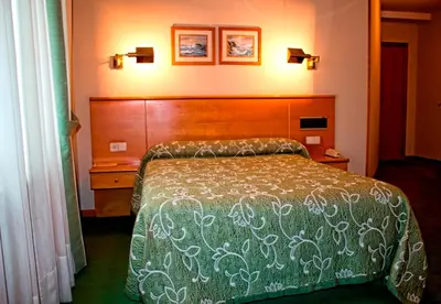 a bedroom with a bed and two pictures on the wall at Hotel Ramos in Silleda