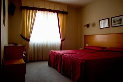 a bedroom with a red bed and a large window at Hotel Ramos in Silleda