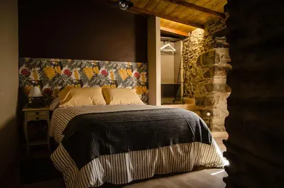a bedroom with a large bed with a stone wall at Casa Turística Viladonatus (Ribeira Sacra) in Doade