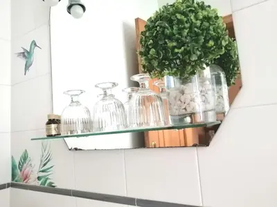 a bathroom shelf with glass jars and a plant at Casa Licerio in Samos