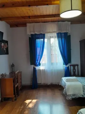 a room with two beds and a window with blue curtains at Casa Licerio in Samos