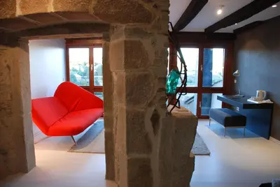 a living room with a red chair and a table at Posada Real La Pascasia in Puebla de Sanabria