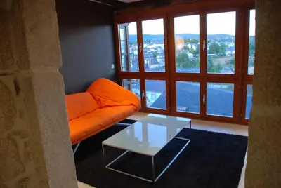 a living room with an orange couch and a glass table at Posada Real La Pascasia in Puebla de Sanabria