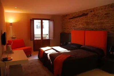a bedroom with a bed and a chair and a window at Posada Real La Pascasia in Puebla de Sanabria