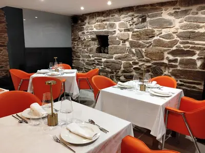 a restaurant with tables and chairs and a stone wall at Posada Real La Pascasia in Puebla de Sanabria