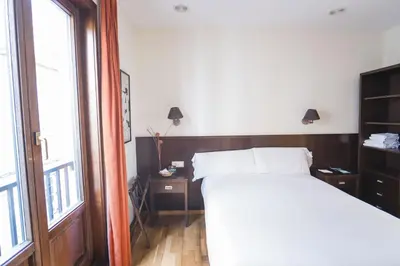 a bedroom with a white bed and a window at Hotel Alda Algalia in Santiago de Compostela