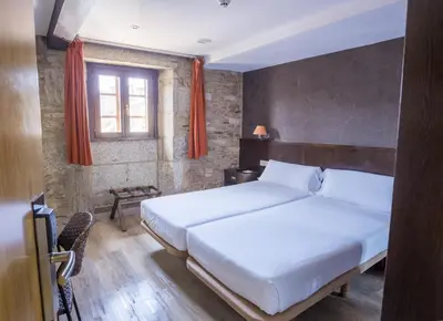a bedroom with a large white bed and a window at Hotel Alda Algalia in Santiago de Compostela