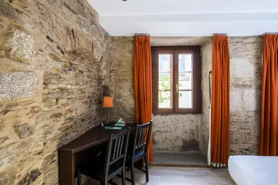 a stone walled room with a desk and a window at Hotel Alda Algalia in Santiago de Compostela