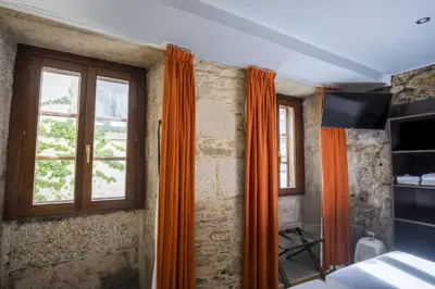 a bedroom with orange curtains and a window at Hotel Alda Algalia in Santiago de Compostela