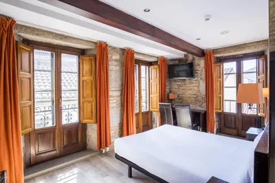 a bedroom with a bed and some windows at Hotel Alda Algalia in Santiago de Compostela