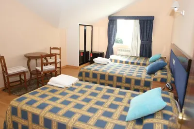 a hotel room with three beds and a table at Hotel Santa Cruz in Montaos