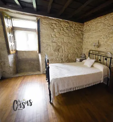 a bedroom with a bed in a room with a window at As Casas Ribeira Sacra in Chantada
