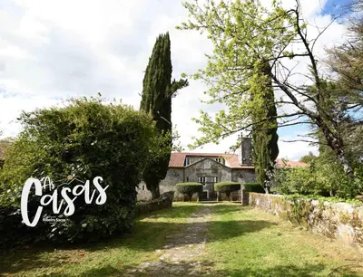 an old stone house with a garden and trees at As Casas Ribeira Sacra in Chantada