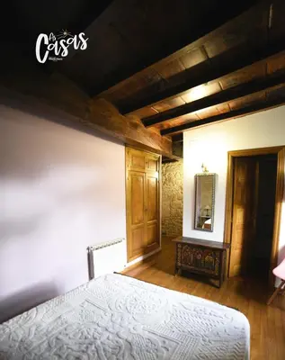 a bedroom with a white bed and wooden floors at As Casas Ribeira Sacra in Chantada
