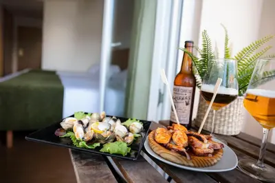 a table with two plates of food and a glass of wine at Hotel Crisol de las Rías in Miño