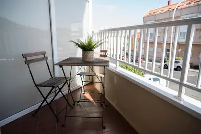 a table and two chairs on a balcony with a window at Hotel Crisol de las Rías in Miño