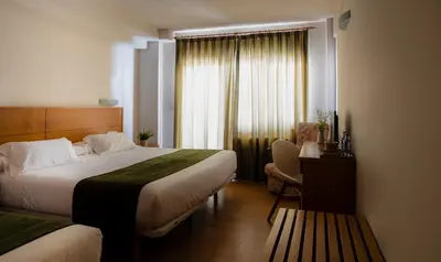 a hotel room with two beds and a window at Hotel Crisol de las Rías in Miño
