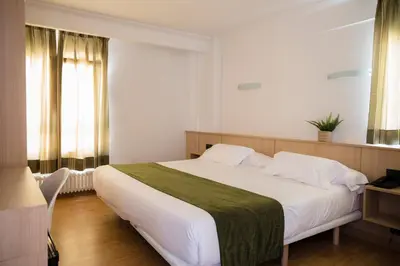 a bedroom with a large bed with white sheets at Hotel Crisol de las Rías in Miño