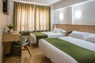 a hotel room with two beds and a desk at Hotel Crisol de las Rías in Miño