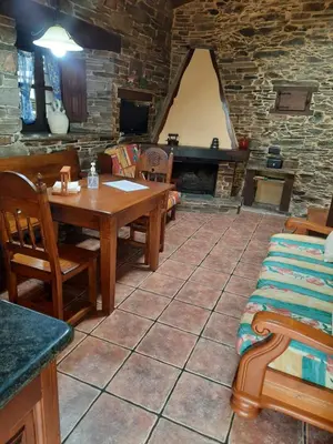 a room with a table and chairs and a stone wall at Casa Viduedo in Santa Eulalia de Oscos