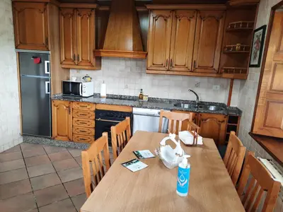 a kitchen with a wooden table and a refrigerator at Casa Viduedo in Santa Eulalia de Oscos