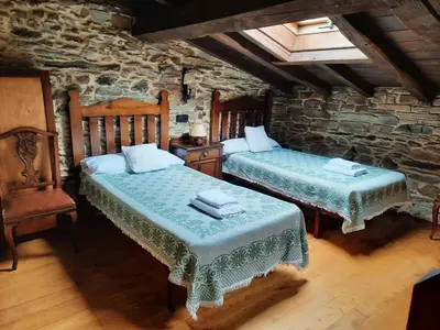 a bedroom with two beds in a stone room at Casa Viduedo in Santa Eulalia de Oscos