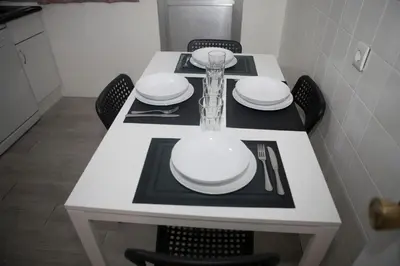 a white table with chairs and white plates on it at El Apartamento de María in Lugo