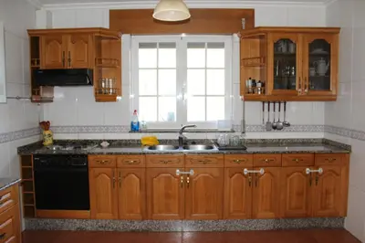 a kitchen with wooden cabinets and a sink and a window at Casa do Xastre in Baralla