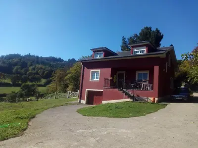 a red house with a car parked in front of it at Casa do Xastre in Baralla