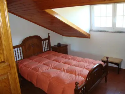 a bedroom with a large bed with an orange comforter at Casa do Xastre in Baralla