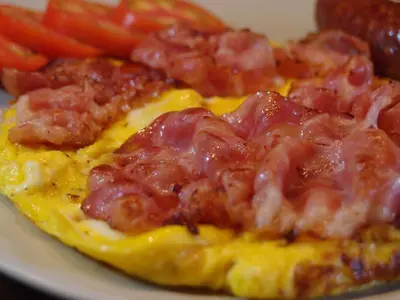 a plate of eggs with meat and tomatoes on it at Albergue Casa del Pescador in Ambasmestas