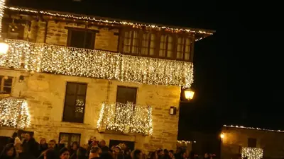 a group of people standing in front of a building with christmas lights at Casa la Devesa de Sanabria in Remesal