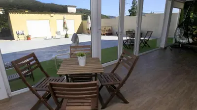 a patio with a wooden table and chairs with a view of a pool at El Albergue del Montero in Mondoñedo