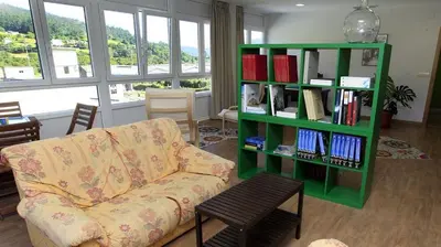 a living room with a couch and a book shelf with books at El Albergue del Montero in Mondoñedo