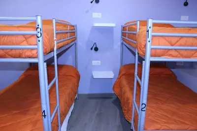 two bunk beds in a room with orange sheets at Albergue Linares in Santiago de Compostela