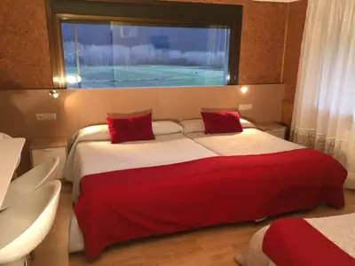 a bedroom with two beds with red pillows and a window at Casa Blanco Conde in Laza