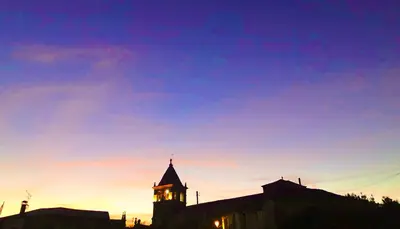 a building with a clock tower at sunset at Casa Blanco Conde in Laza